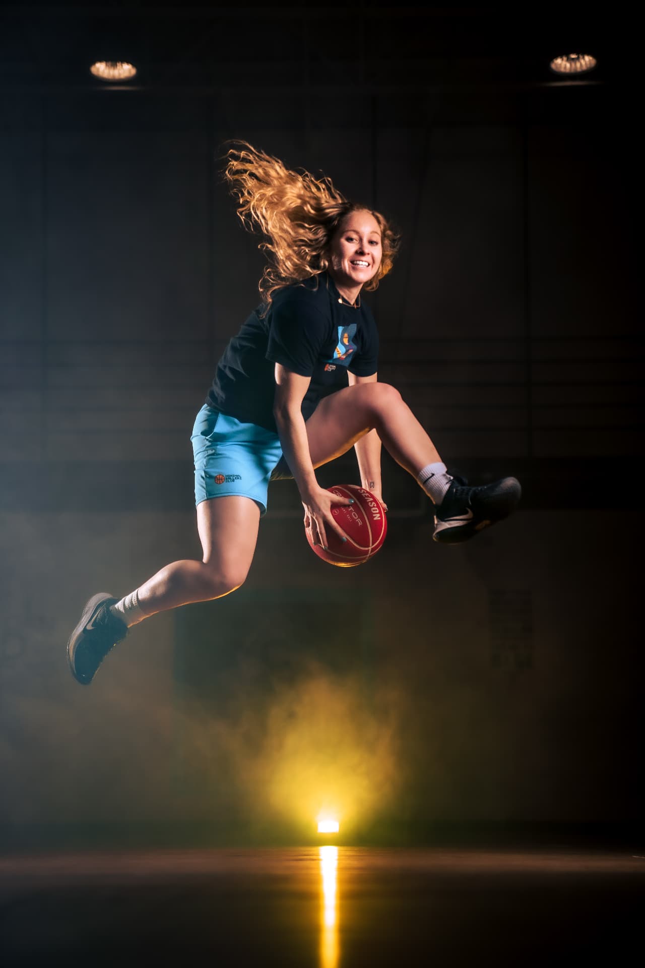 Hannah Mortimer mid-air with a basketball between her legs