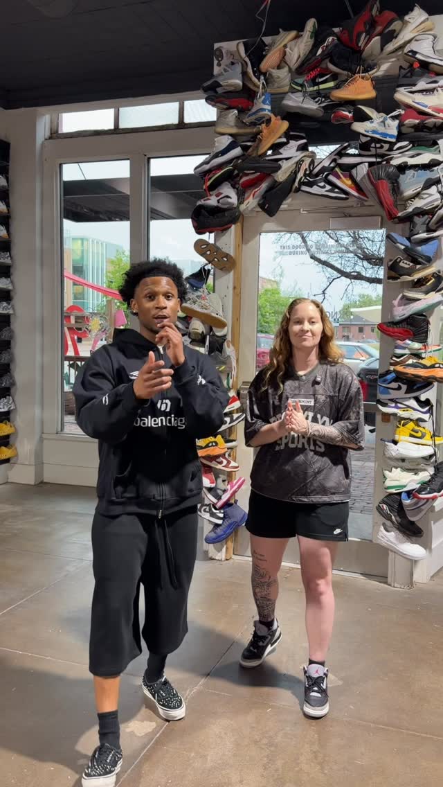 Two people stand in a shoe store in front of a doorway framed with rows of sneakers