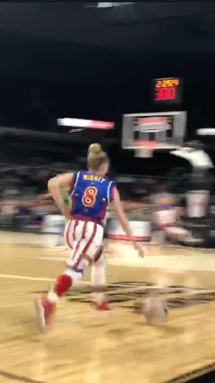 A basketball player wearing jersey number 8 runs across the court inside an indoor arena